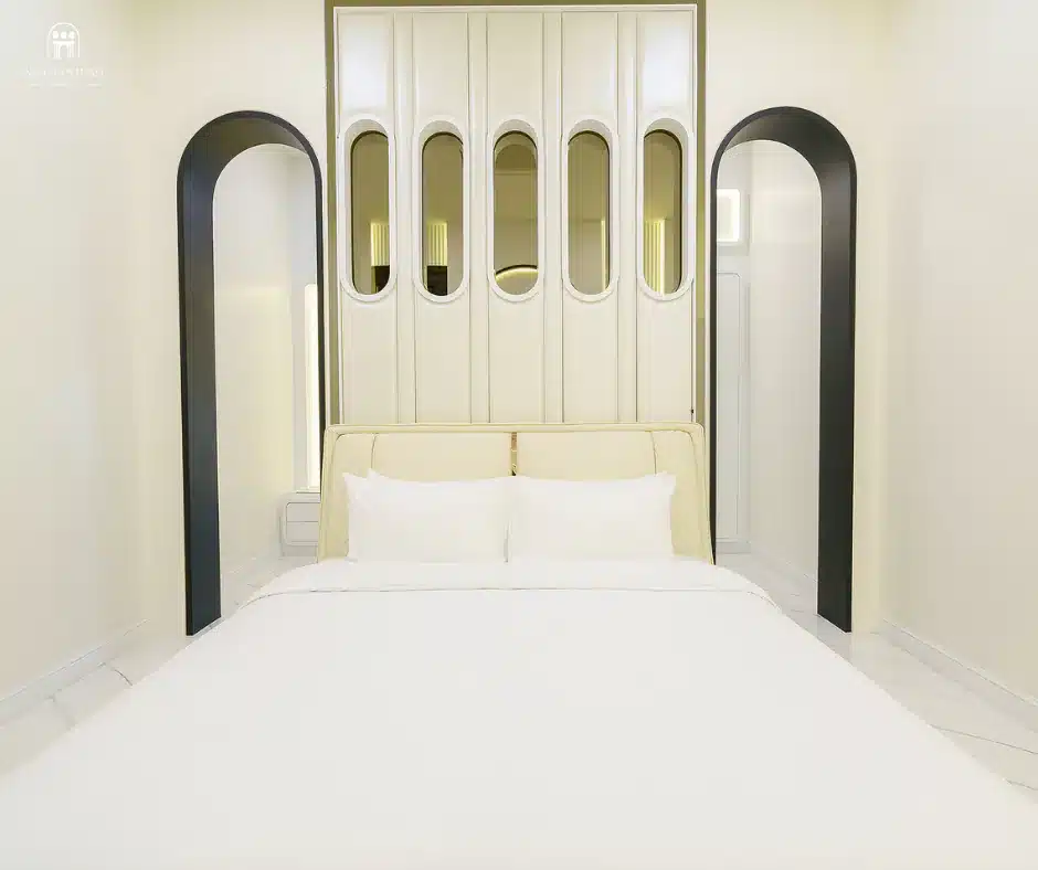 เตียงสีขาวในห้องที่มีหน้าต่างโค้งอันเงียบสงบในสมุทรสงคราม ที่พักสมุทรสงคราม