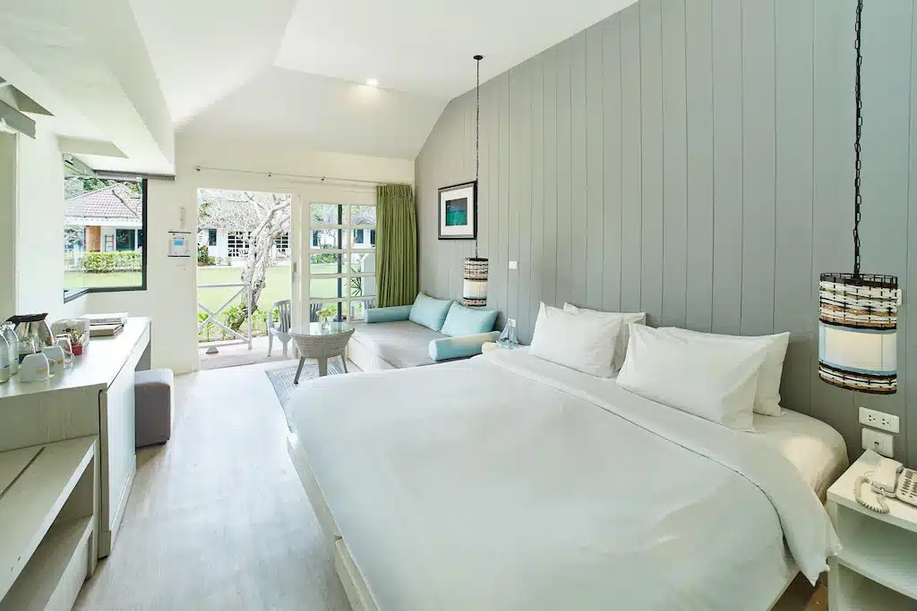 ห้องพักที่มีเตียงสีขาวและระเบียงที่หาดแม่รำพึงที่พัก หาดแม่รําพึงที่พัก