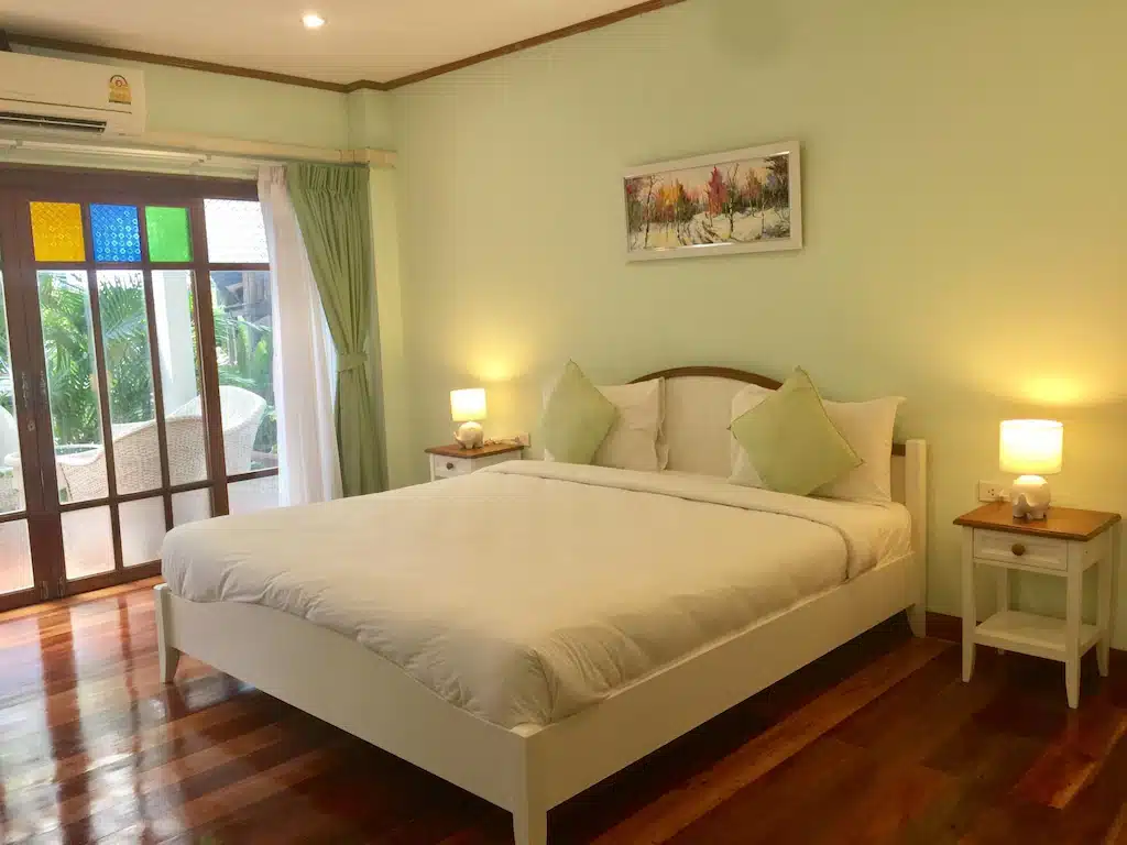ห้องนอนที่มีผนังสีเขียวและพื้นไม้ ตั้งอยู่ในโรงแรมแห่งหนึ่งในจังหวัดศรีสะเกษ  ที่พักศรีสะเกษ ประเทศไทย