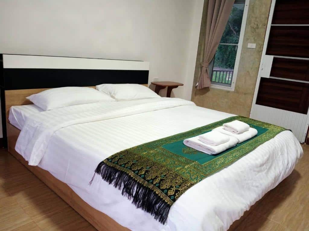 เตียงในห้องที่มีผ้าเช็ดตัวอยู่บนที่พักของบ้านรักไทย ที่พักบ้านรักไทย