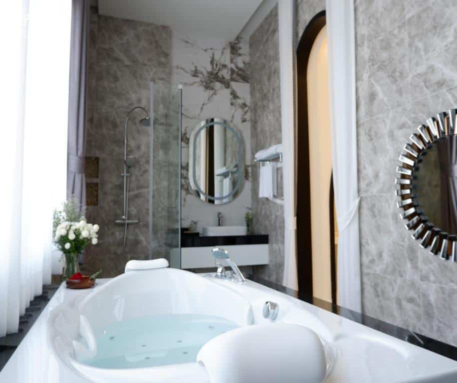ห้องน้ำสีขาวพร้อมอ่างอาบน้ำและกระจกในโรงแรมสมุทรสงคราม ที่พักสมุทรสงคราม