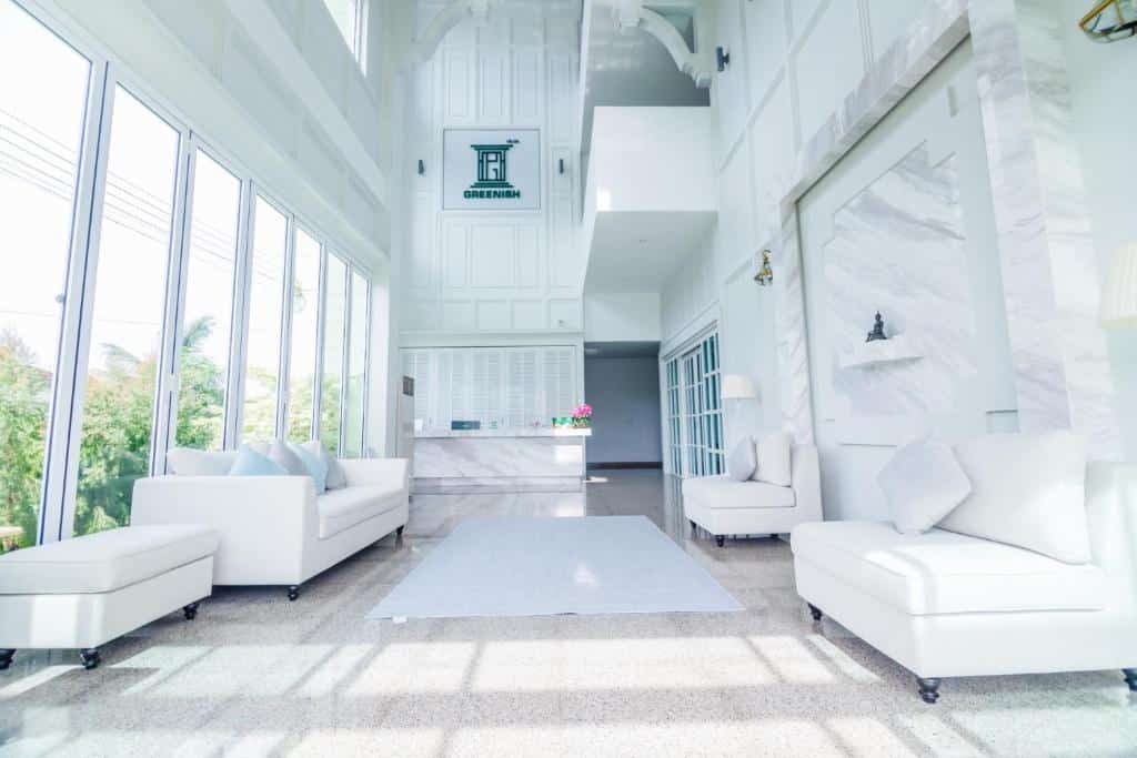 ที่พักระนอง ห้องนั่งเล่นสีขาวพร้อมหน้าต่างบานใหญ่และเฟอร์นิเจอร์สีขาวในโรงแรมริมชายหาดในจังหวัดระนอง ประเทศไทย