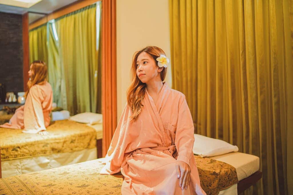 ผู้หญิงในชุดคลุมสีชมพูนั่งอยู่บนเตียงที่โรงแรมสปาในจังหวัดพังงา ที่พักพังงา
