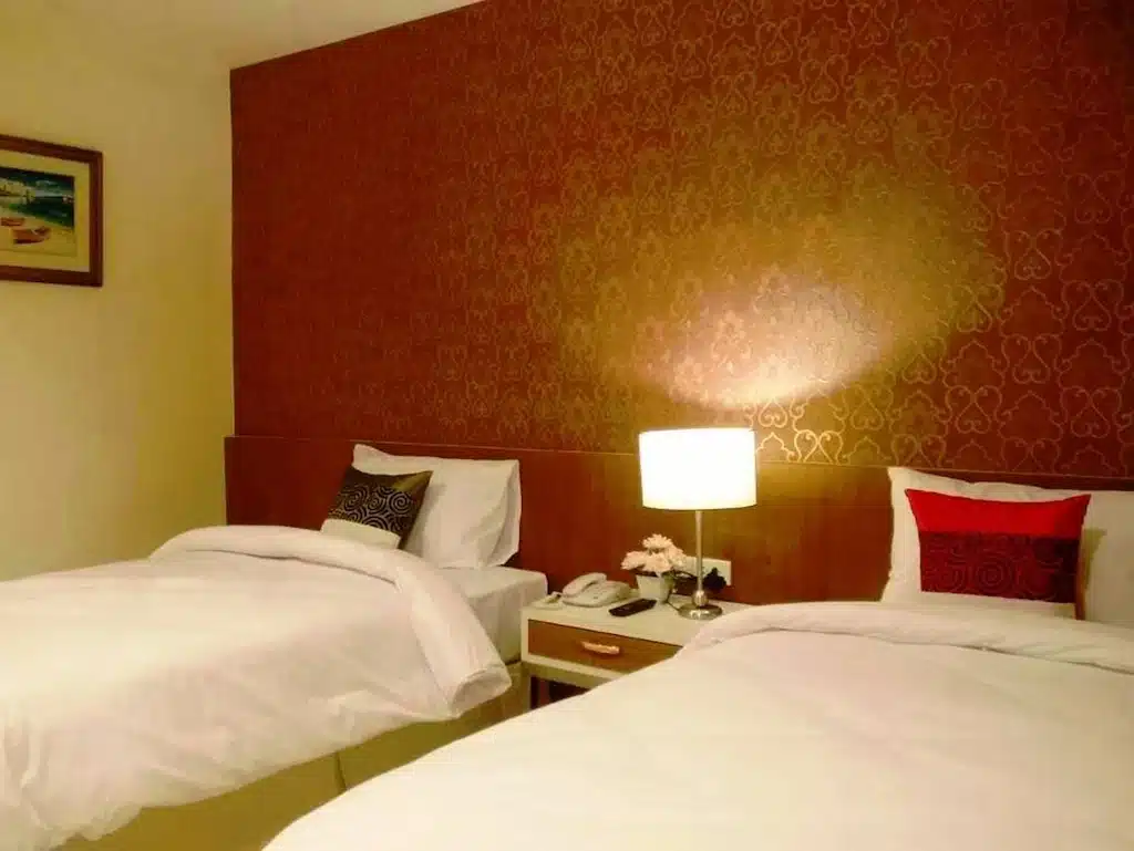 เตียงสองเตียงในห้องพักของโรงแรมที่มีผนังสีน้ำตาล พูลวิลล่านครนายก