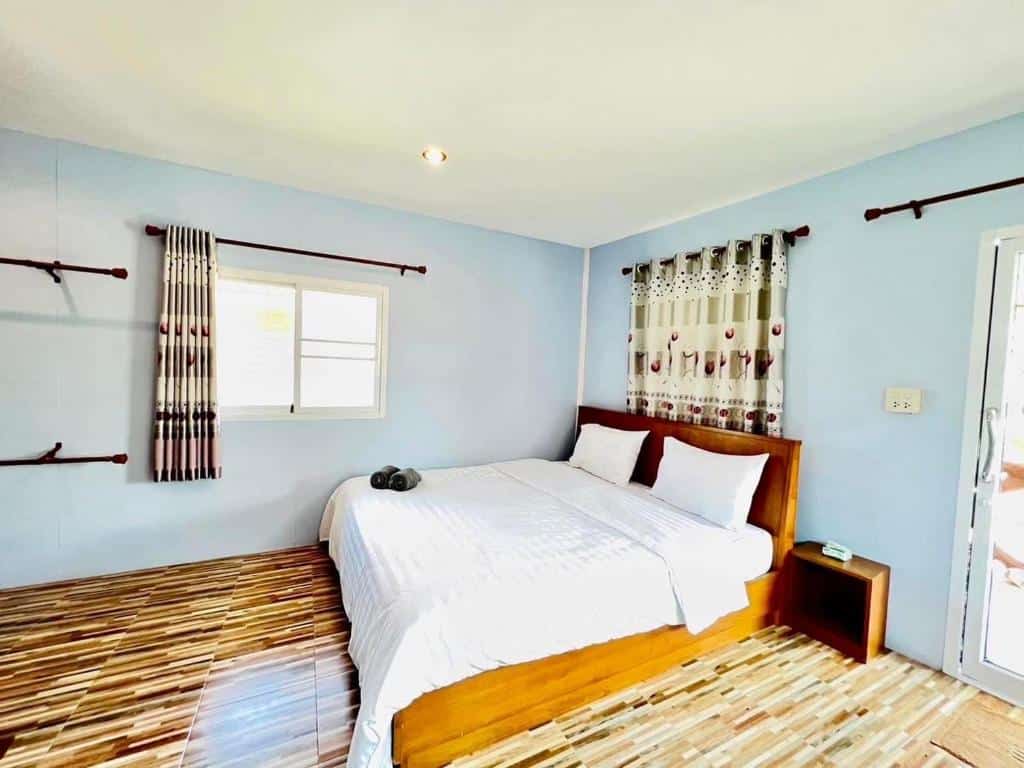 เตียงในห้องที่มีผนังสีฟ้าและพื้นไม้ โรงแรมพัทลุง