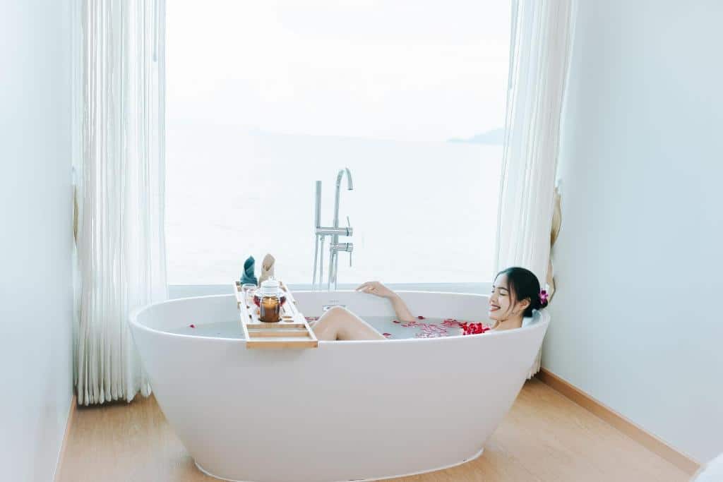 ผู้หญิงกำลังพักผ่อนในอ่างอาบน้ำสีขาวพร้อมชมวิวทะเลที่โรงแรมริมชายหาดในจังหวัดสตูล ที่พักสตูล