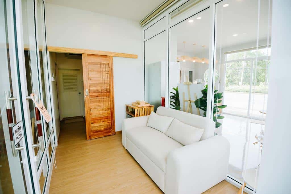 ห้องนั่งเล่นพร้อมโซฟาสีขาวและประตูกระจกในโรงแรมริมชายหาดในจังหวัดสตูล ที่พักสตูล