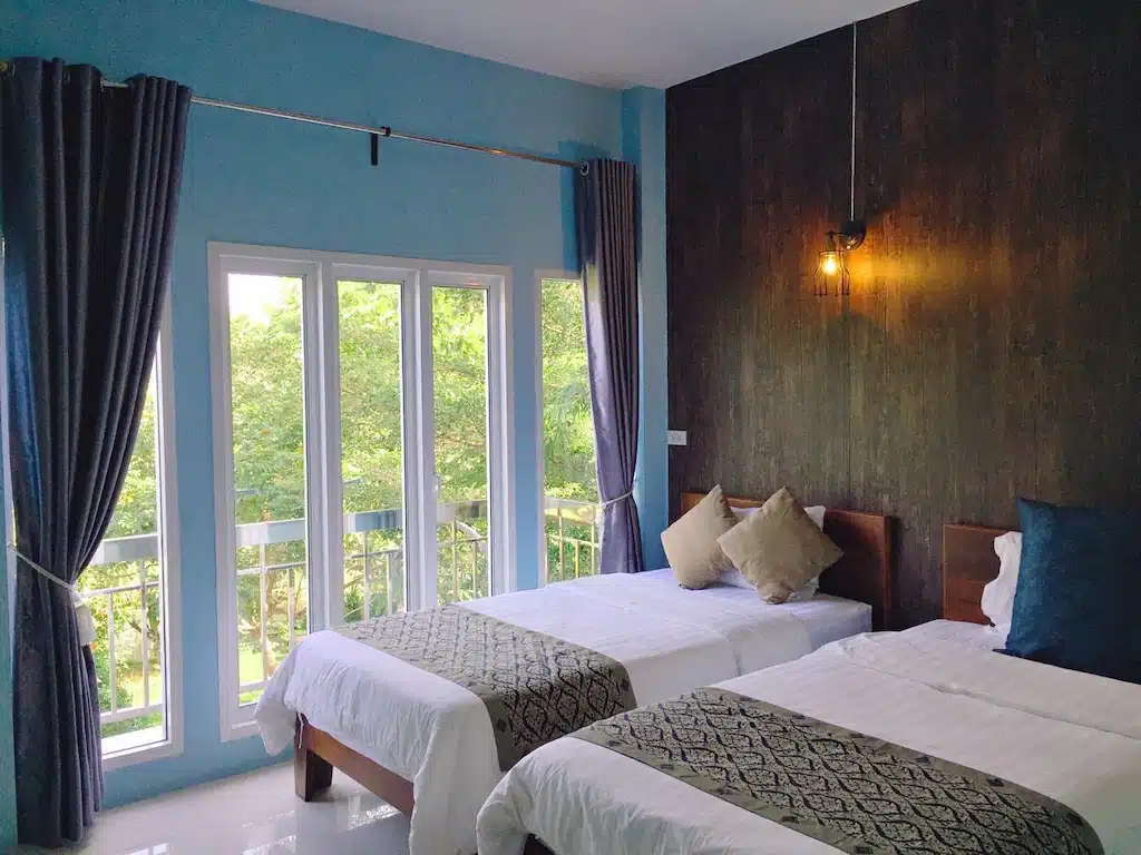 เตียงสองเตียงในห้องแสนสบายพร้อมผนังสีฟ้าที่ร้านอาหารพัทลุง ที่พักสุพรรณบุรี