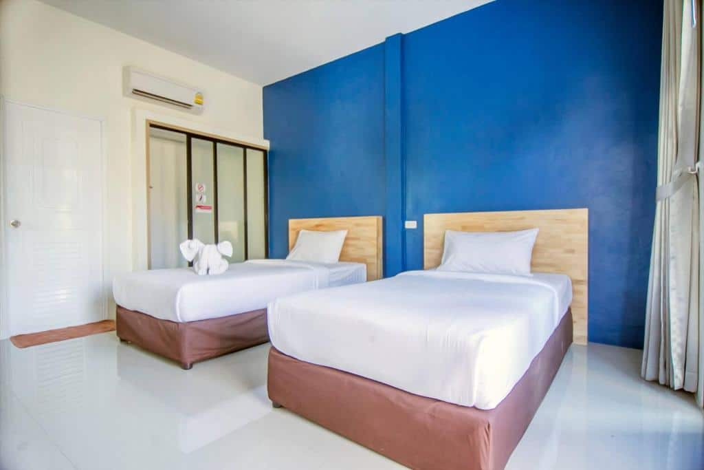 เตียงสองเตียงในห้องแสนสบายผนังสีฟ้า ตั้งอยู่ในที่พักอันมีเสน่ห์ในจังหวัดตรัง ที่พักตรัง
