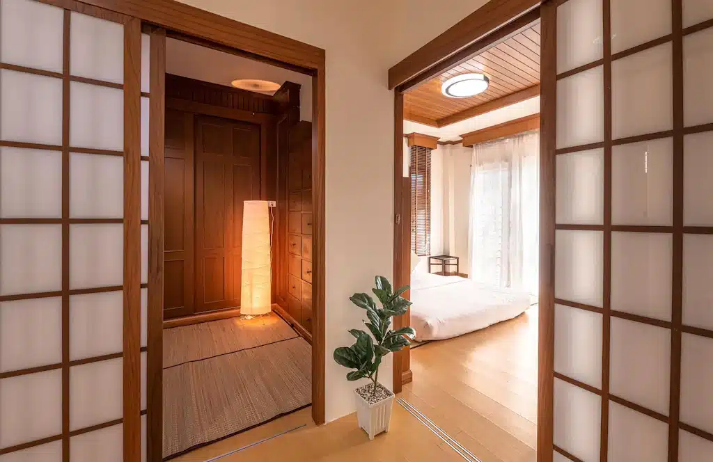 ที่พักระนอง ห้องนอนสไตล์ญี่ปุ่นพร้อมประตูไม้และพื้นไม้ ตั้งอยู่ในโรงแรมริมชายหาดในจังหวัดระนอง ประเทศไทย
