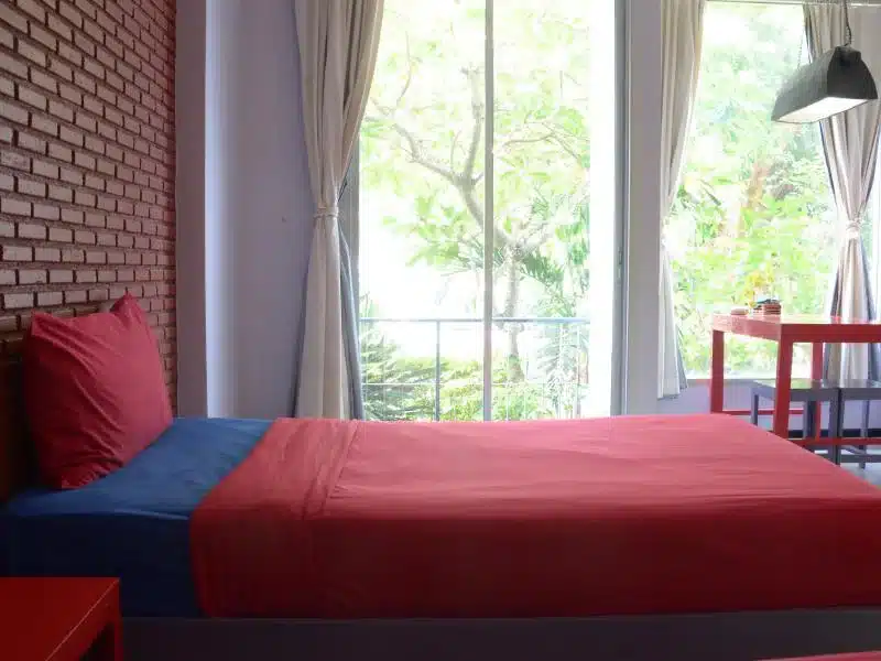ห้องพักในโรงแรมที่มี 2 เตียงและเครื่องนอนสีสันสดใสในสีแดงและน้ำเงิน โรงแรมศรีสะเกษ