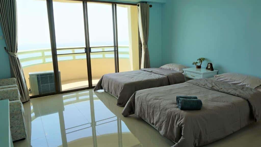 ห้องนอนริมชายหาดพร้อมเตียง 2 เตียงและระเบียงที่มองเห็นวิวทะเล หาดแม่รำพึงที่พัก