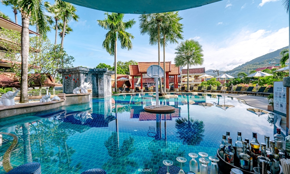 สระว่ายน้ำชนาลัย ฟลอรา รีสอร์ท ล้อมรอบด้วยต้นปาล์ม Chanalai Flora Resort
