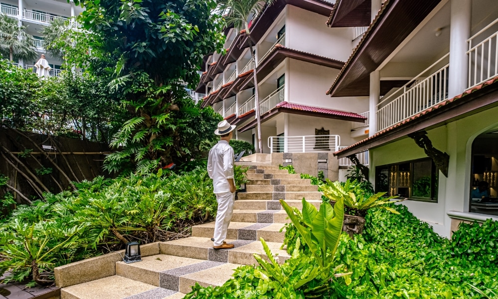 ชายคนหนึ่งยืนอยู่บนขั้นบันไดของชนาลัย ฟลอรา รีสอร์ท Chanalai Flora Resort