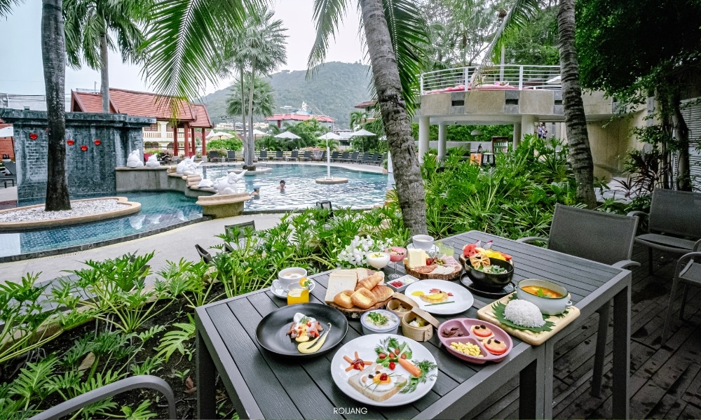 ชนาลัย ฟลอรา รีสอร์ท มีทัศนียภาพริมสระน้ำที่งดงามราวภาพวาด พร้อมด้วยโต๊ะที่ประดับประดาด้วยอาหารเลิศรสและเครื่องดื่มเพื่อความสดชื่น Chanalai Flora Resort