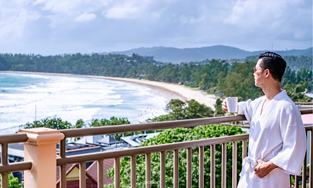Chanalai garden resort ผู้ชายยืนอยู่บนระเบียงที่ชนาลัย การ์เดน รีสอร์ท มองเห็นทะเล