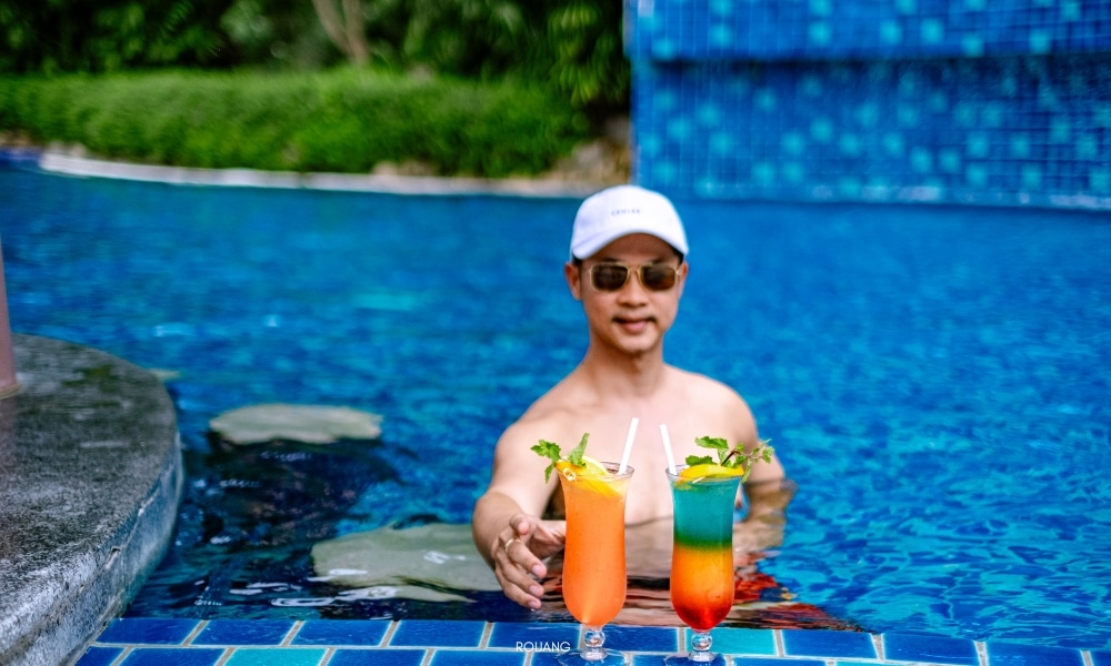 ผู้ชายกำลังเพลิดเพลินกับเครื่องดื่มที่สระว่ายน้ำชนาลัย การ์เดน รีสอร์ท Chanalai garden resort
