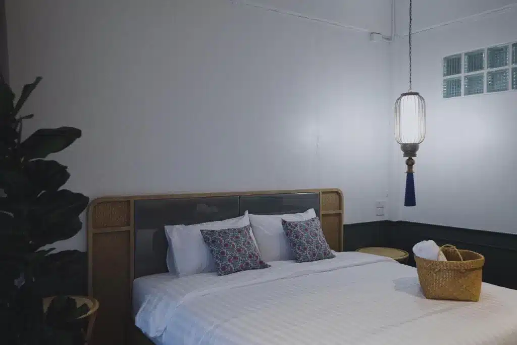 เตียงแสนสบายในห้องที่มีโคมไฟแขวนอยู่เหนือโรงแรมใน โรงแรมในตรัง