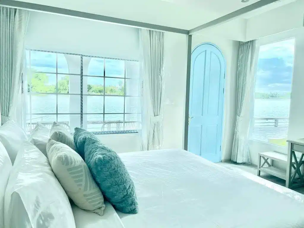 เตียงสีขาวในห้องที่มองเห็นวิวน้ำสมุทรสงครา ที่พักสมุทรสงคราม