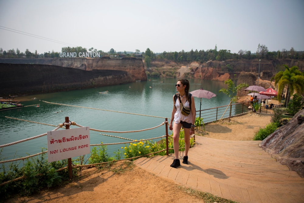 ผู้หญิงยืนอยู่บนเส้นทางริมแม่น้ำระหว่างเที่ยวสงกรานต์ ที่เที่ยวหน้าร้อน สวนน้ำ