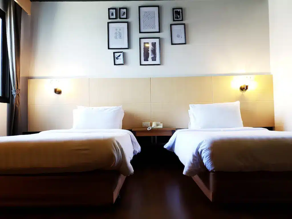 เตียงสองเตียงในห้องแสนสบายที่ตกแต่งด้วยรูปภาพบนผนัง โรงแรมปัตตานี