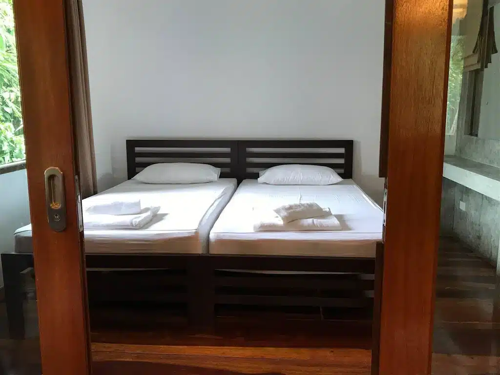 เตียงสองเตียงในห้องประตูไม้ ที่พักสมุทรสาคร