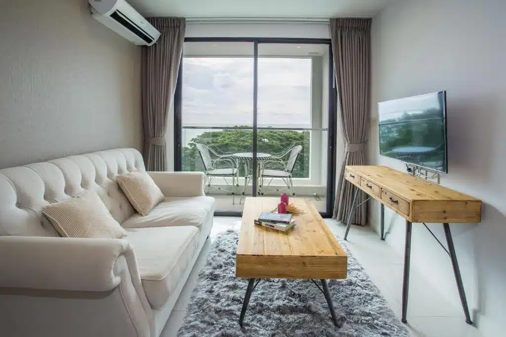 ห้องนั่งเล่นกว้างขวางพร้อมโซฟาสีขาวและทีวี ตั้งอยู่ในที่พักริมชายหาด ที่พักบางเสร่ติดทะเล