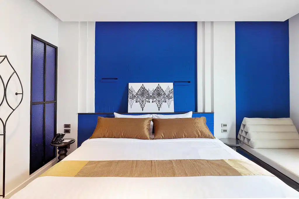 ห้องนอนสีฟ้าและสีขาวในโรงแรมแกลง พร้อมเตียงและเก้าอี้ ที่พักแกลง