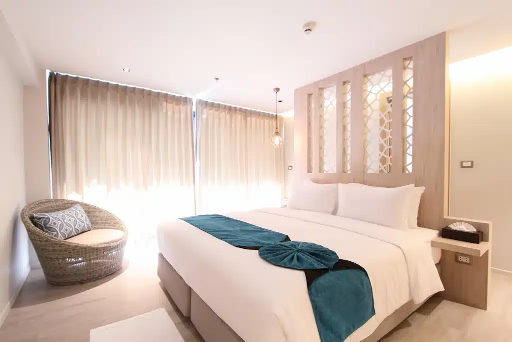 ห้องพักในโรงแรมริมชายหาดพร้อมเตียงสีขาวและผ้าห่มสีน้ำเงิน ที่พักหาดจอมเทียนติดทะเล
