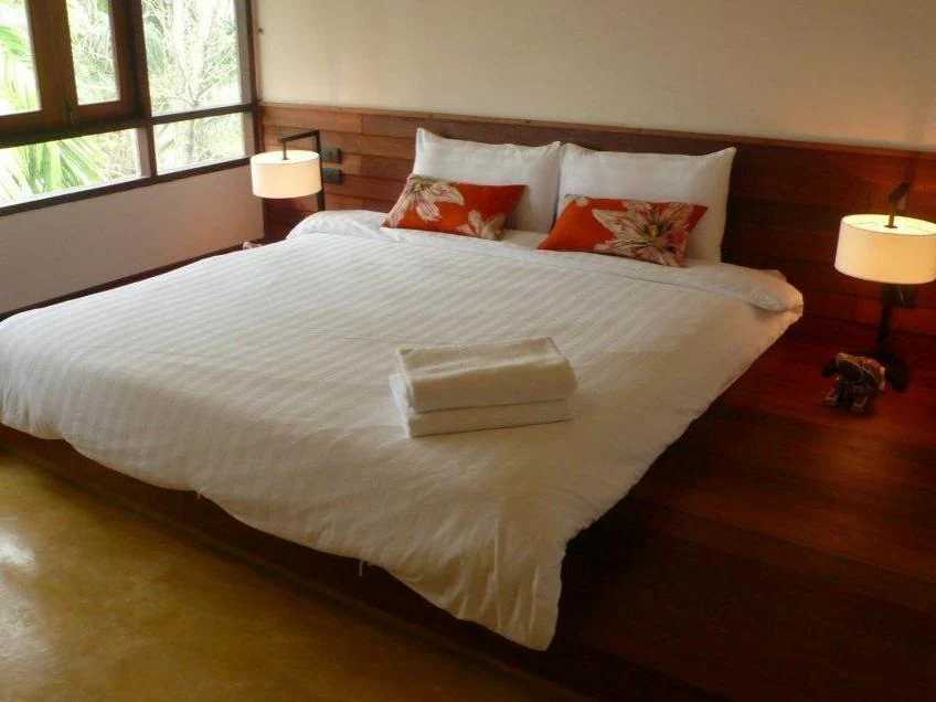 ห้องนอนพร้อมเตียงสีขาวและพื้นไม้