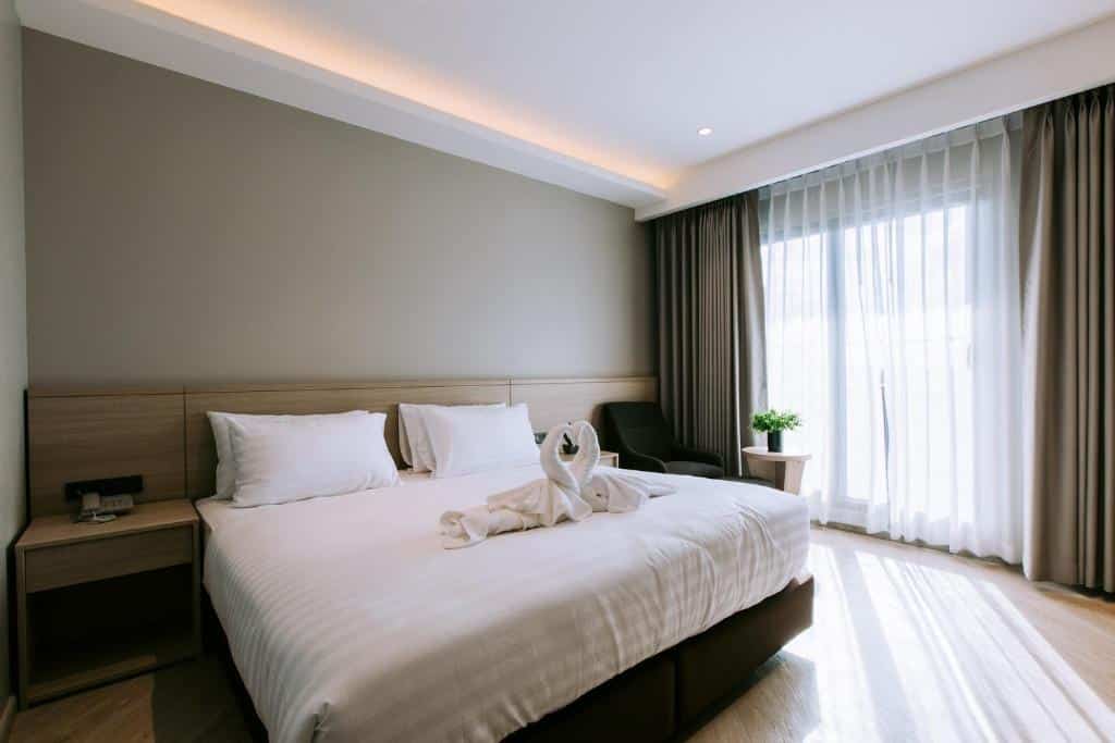 เตียงสีขาวและผ้าเช็ดตัวมีให้ในห้องพักของโรงแรมในจังหวัดนครราชสีมา ที่พักนครราชสีมา