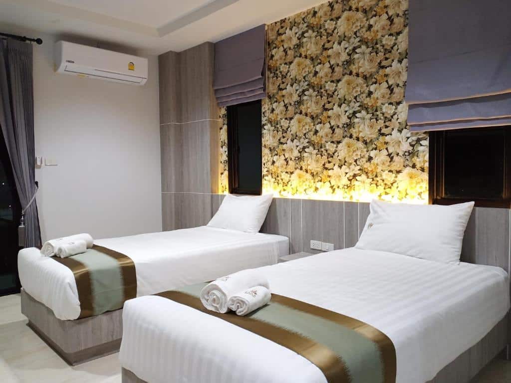 เตียงสองเตียงในห้องที่โรงแรมปัตตานี มีดอกไม้อยู่บนผนัง ที่พักปัตตานี