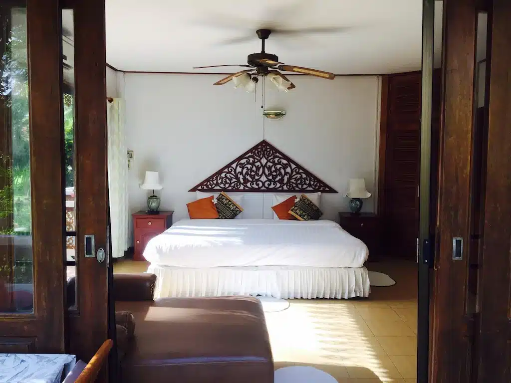ห้องนอนพร้อมเตียงและพัดลมเพดาน ตั้งอยู่ในที่พักริมชายหาด ที่พักแกลง