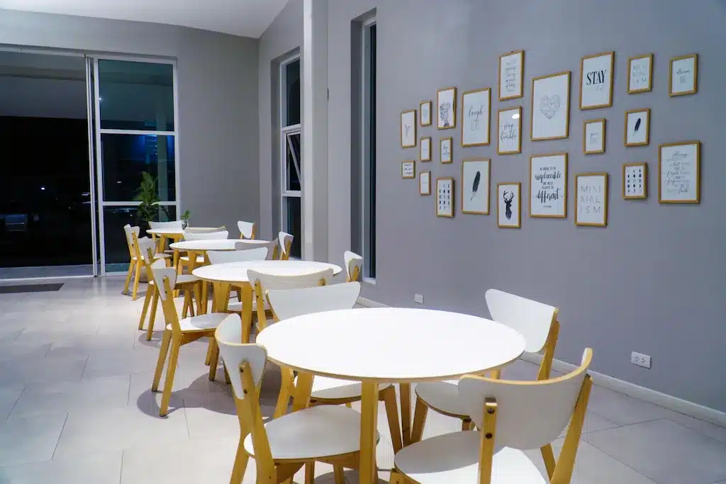 ร้านกาแฟที่มีโต๊ะและเก้าอี้สีขาวและรูปภาพบนผนัง ตั้งอยู่ใน รีสอร์ทปัตตานี 