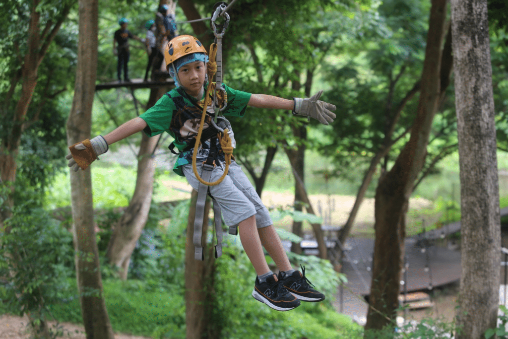 เด็กชายเพลิดเพลินกับการผจญภัยโหนสลิงในป่าอันงดงามของราชบุรี หนึ่งในสถานที่ท่องเที่ยวที่สำคัญในบรรดาสถานที่ท่องเที่ยว  ที่เที่ยวสวนผึ้ง มากมาย เช่น สวนผีเสื้อและฟาร์มกล้วยไม้