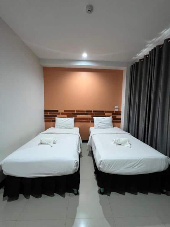 เตียงสองเตียงในห้องพักโรงแรมที่มีผ้าปูที่นอนสีขาวในจังหวัดยโสธร โรงแรมในยโสธร