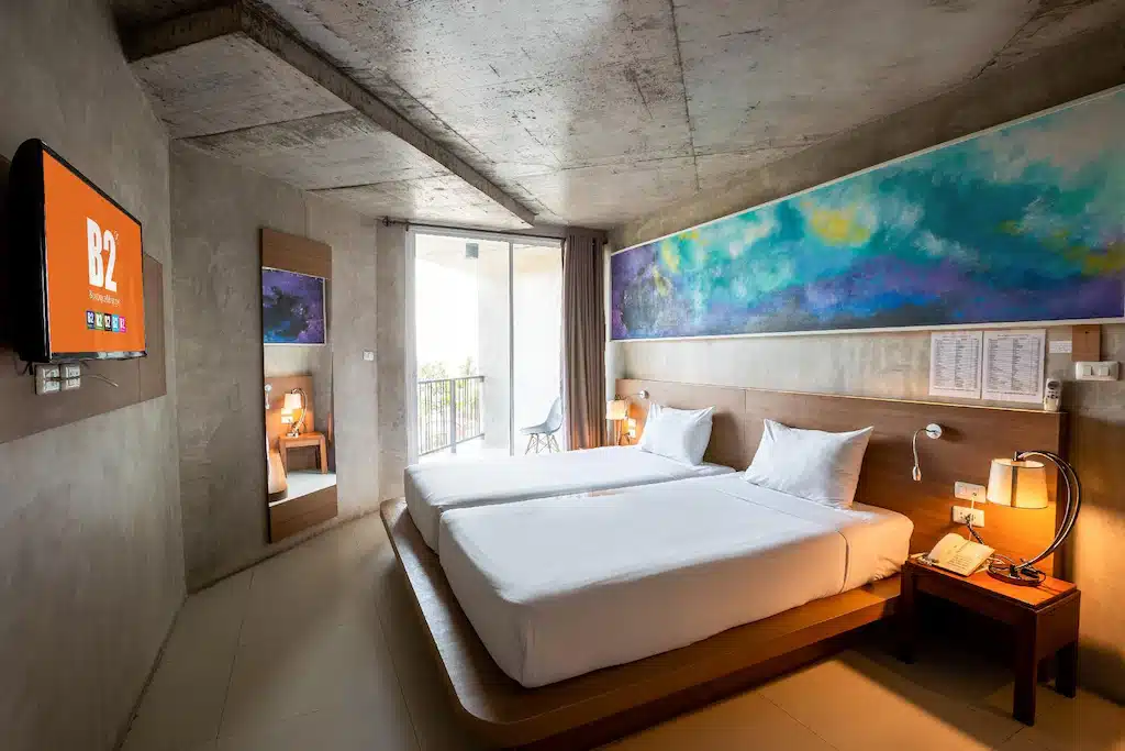มีเตียงสองเตียงและมีภาพวาดบนผนัง โรงแรมหาดจอมเทียนติดทะเล