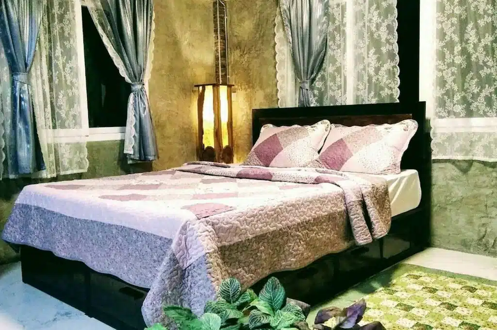 เตียงหรือเตียงในห้องที่มีผ้าห่มสีชมพูม่วงที่ รีสอร์ทสมุทรสาคร
