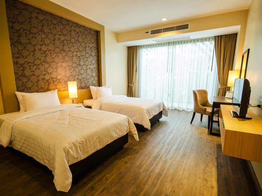 เตียงสองเตียงในห้องพักของโรงแรมที่มีพื้นไม้และวัดอโศการาม วัดอโศการาม
