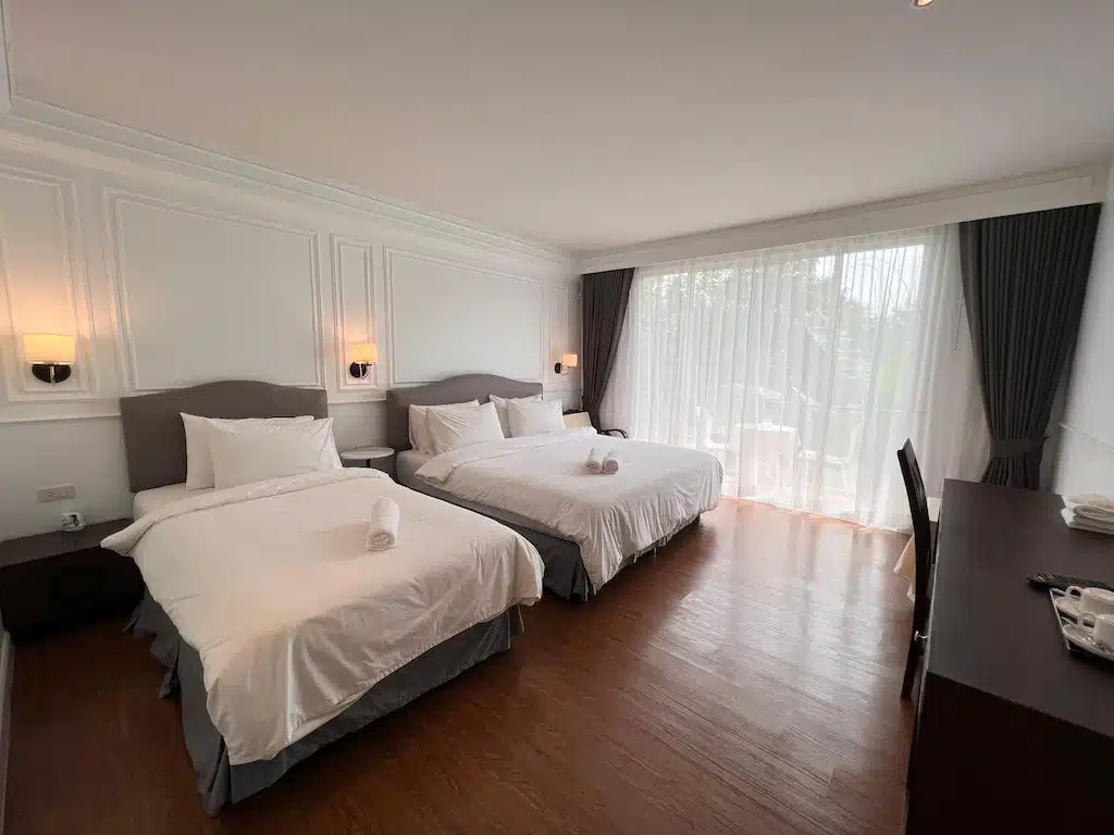 เตียงสองเตียงในห้องพักของโรงแรมที่มีพื้นไม้ ที่เที่ยวสังขละบุรี