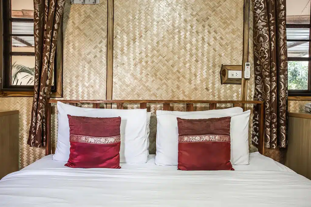 เตียงที่มีผนังไม้และหมอนสีแดงพร้อมเตียง ที่พักอำนาจเจริญ