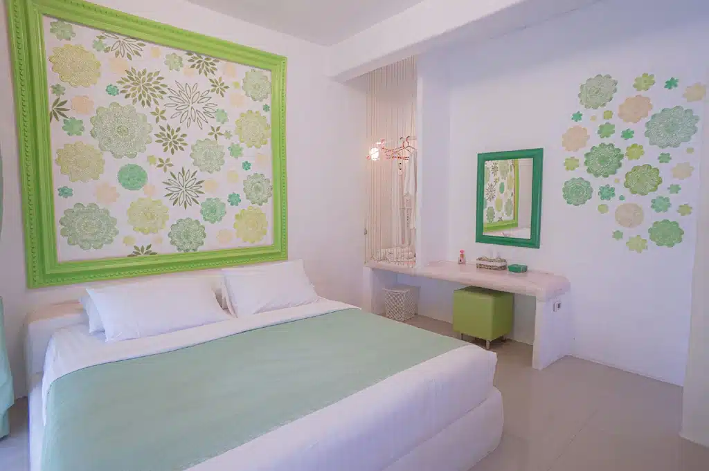 ห้องนอนสีเขียวขาวพร้อมเตียงและกระจก ตั้งอยู่ในพื้นที่ท่องเที่ยวราชบุรี เที่ยวสวนผึ้ง