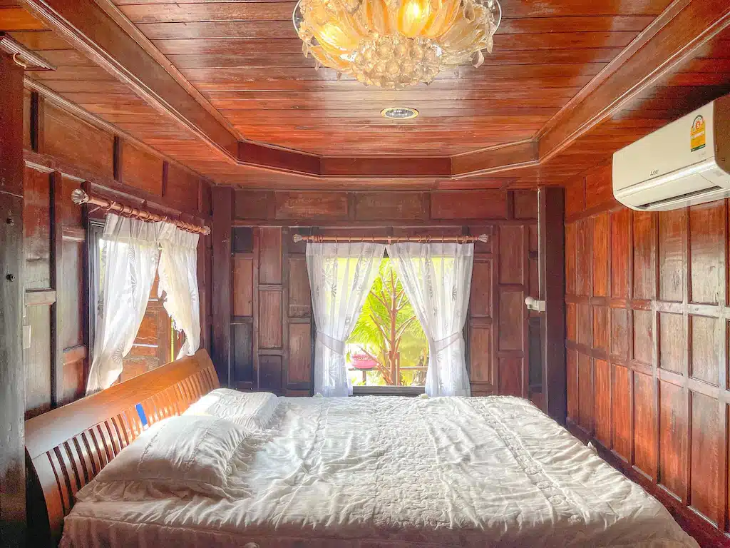 ห้องนอนไม้พร้อมเตียงและพัดลม ตั้งอยู่ใน โรงแรมแกลง