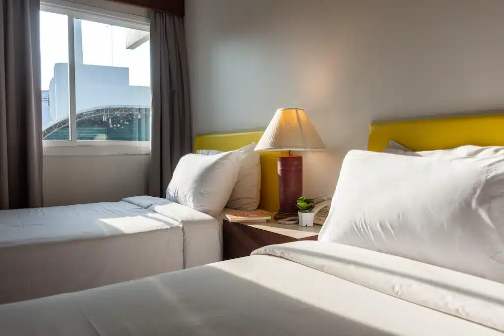 เตียงสองเตียงในห้องพักของโรงแรมที่โรงแรมนครราชสีมาที่มีหัวเตียงสีเหลือง ที่พักนครราชสีมา
