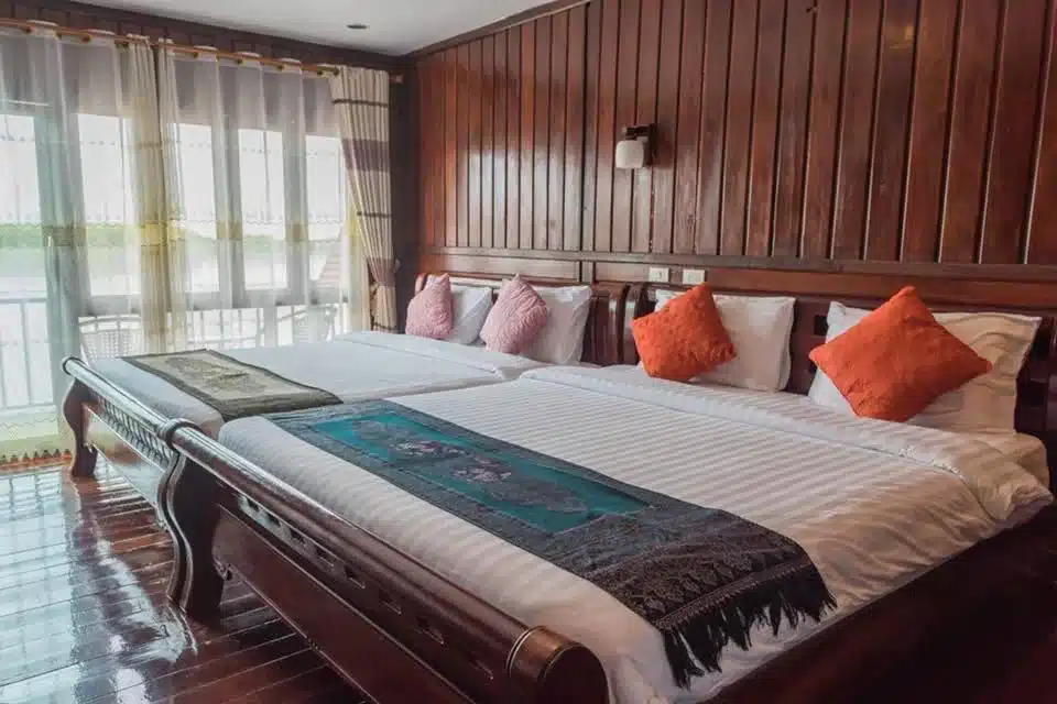 เตียงสองเตียงในห้องพักของโรงแรมที่มีผนังไม้ โรงแรมเลย