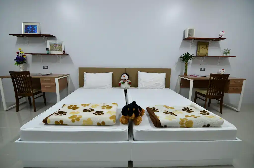 สองเตียงในห้องที่มีตุ๊กตาหมีอยู่บนเตียงที่ รีสอร์ทปทุมธานี