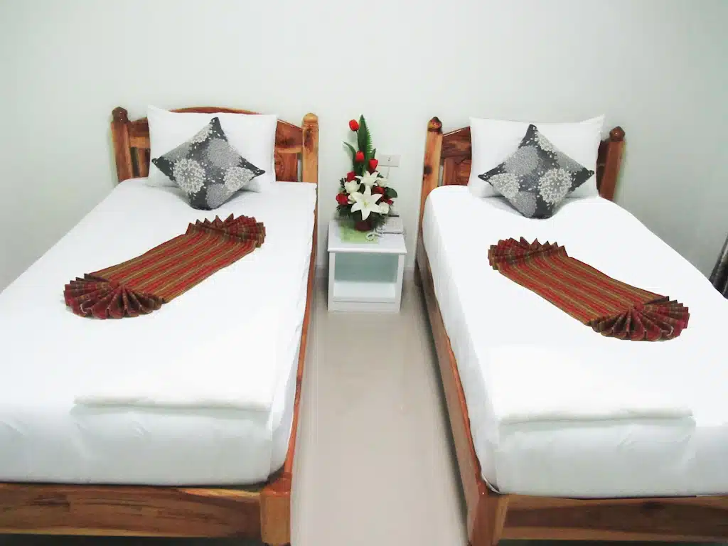 สองเตียงในบริการร้อยเอ็ดพร้อมผ้าปูที่นอนและหมอนสีขาว โรงแรมร้อยเอ็ด