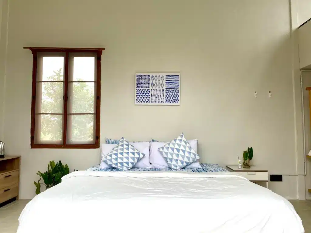 ห้องนอนที่มีเตียงสีขาวและหมอนสีฟ้าในโรงแรมเลย ที่พักเมืองเลย