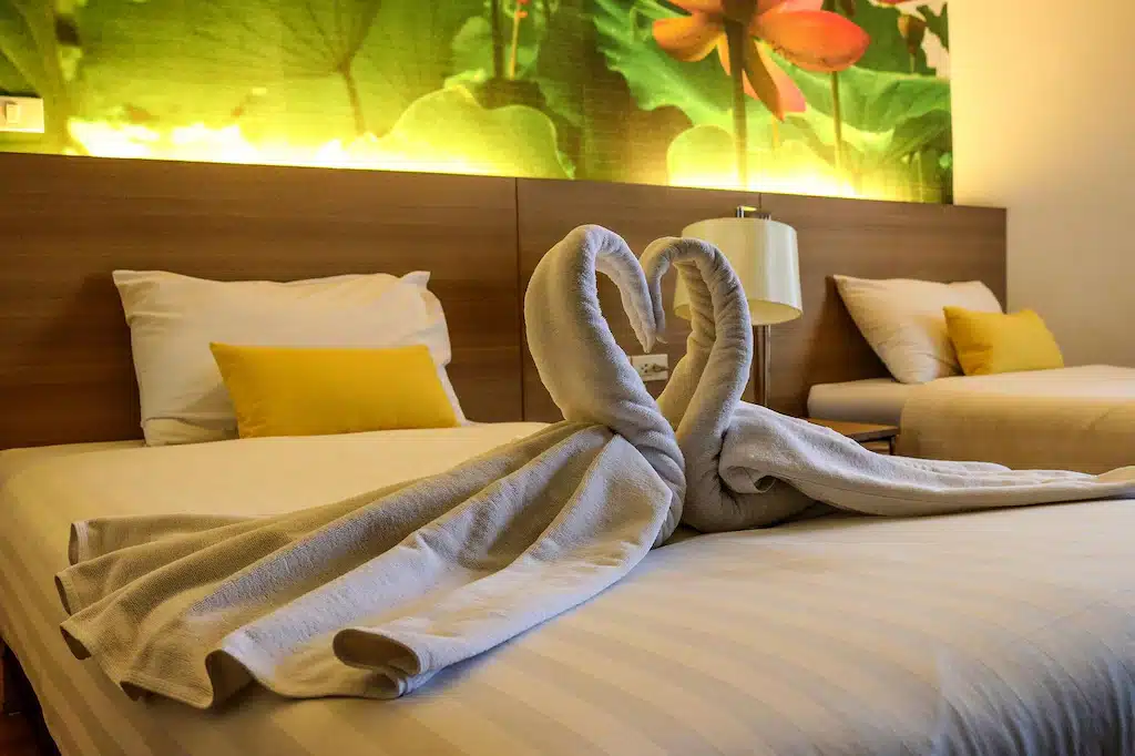 มีเตียงที่มีผ้าเช็ดตัวหงส์ 2 ผืนอยู่บน รีสอร์ทปทุมธานี