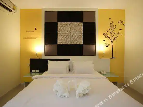 เตียงสีขาวในห้องที่มีผนังสีเหลืองในสไตล์โสธร โรงแรมในยโสธร
